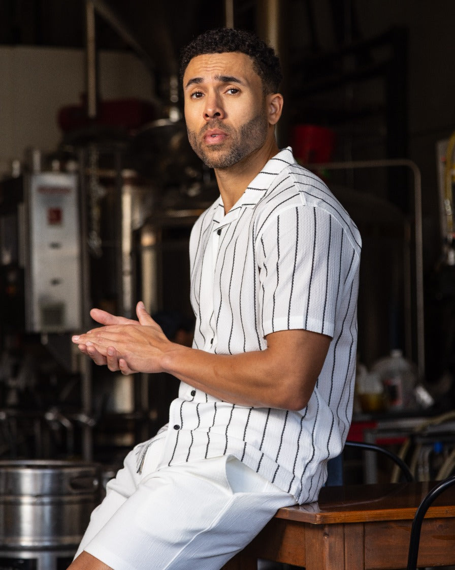 Men's white camp shirt with vertical black pinstripes, short sleeves, open collar