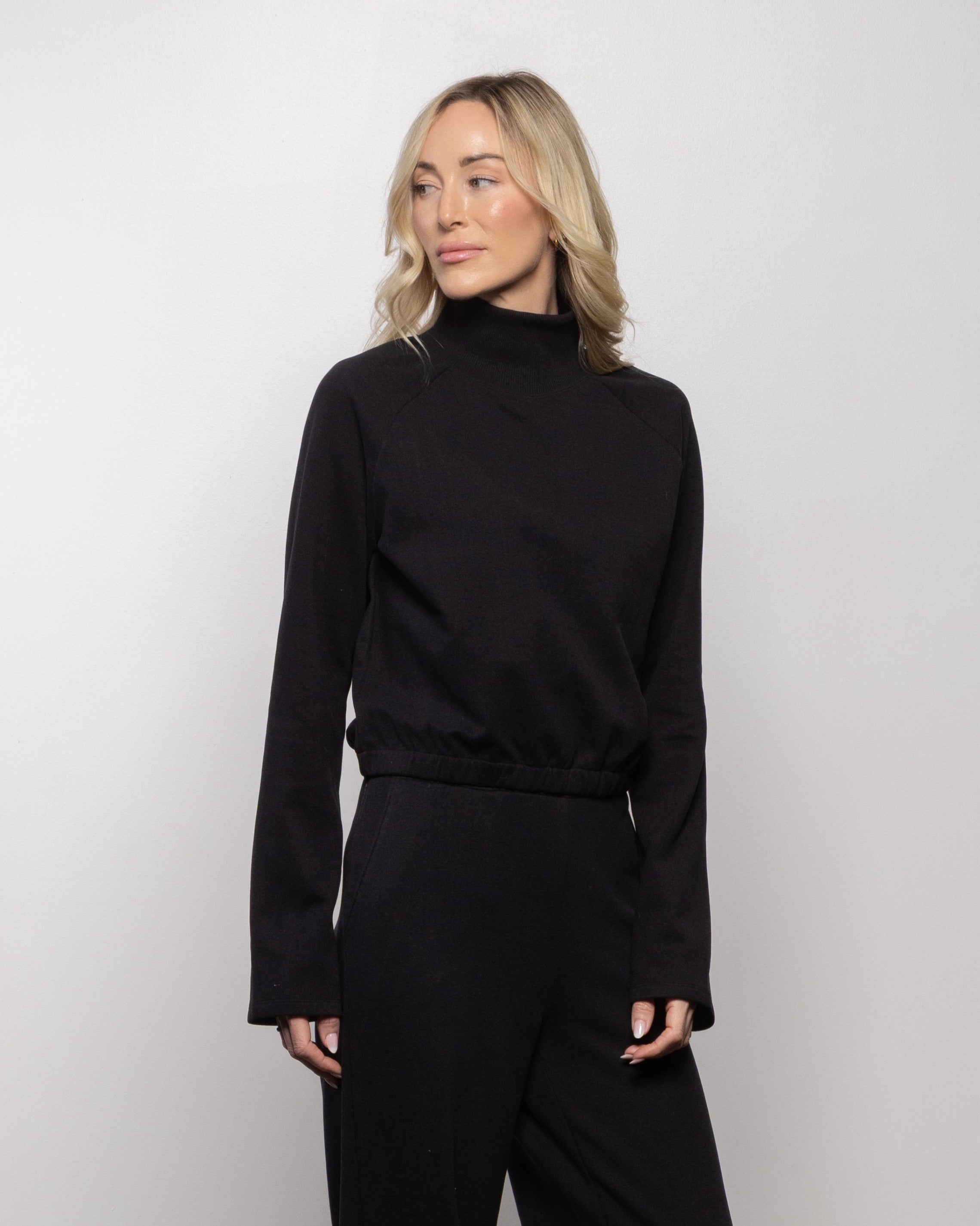 Jet black mock-neck long-sleeve top with gathered hem and smooth fabric