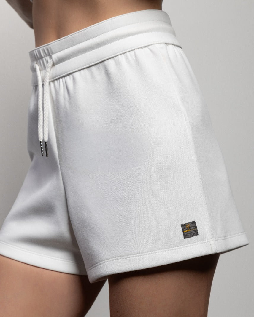 White shorts with drawstring, side pocket, and small logo patch
