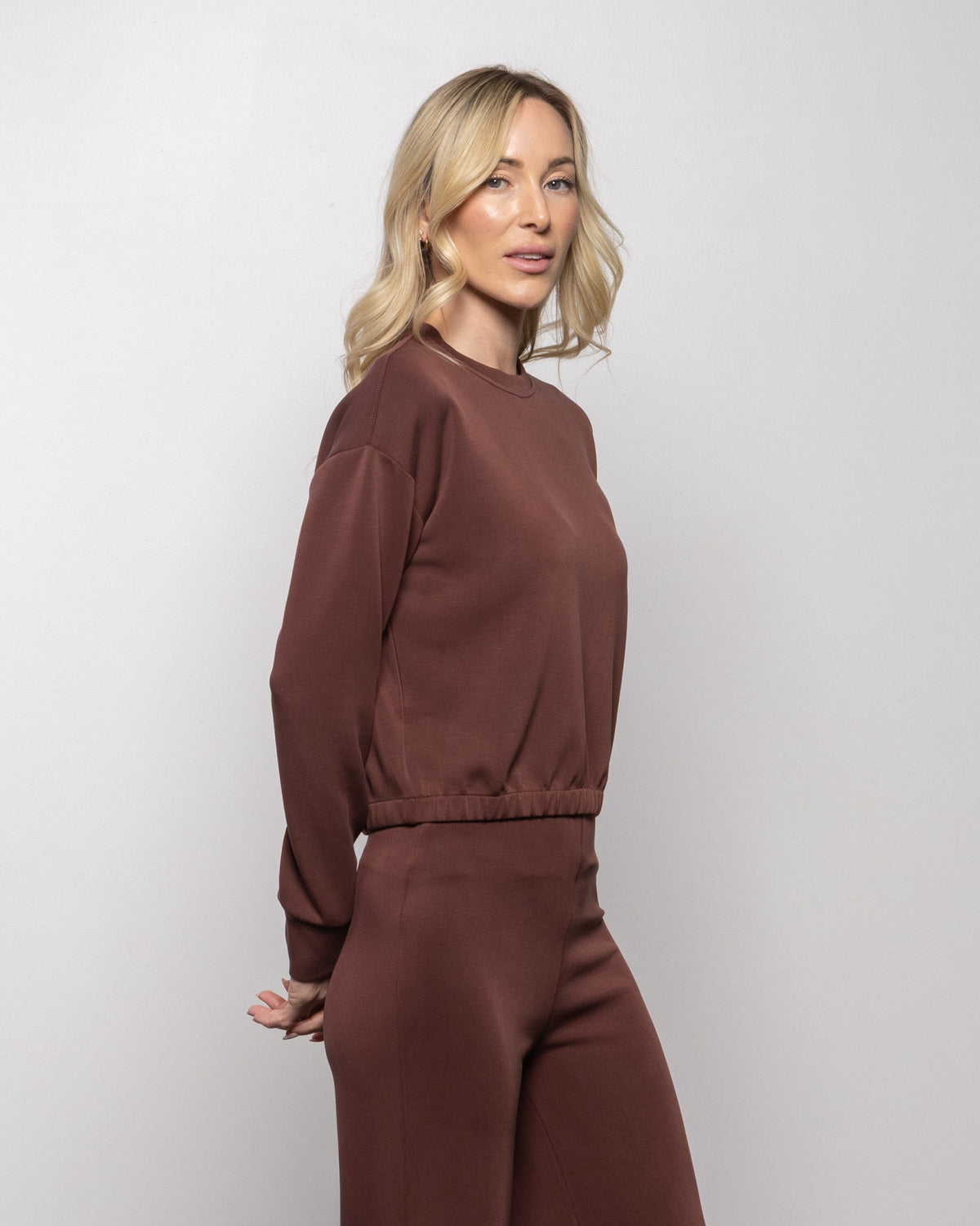 Brick brown crewneck sweatshirt, side view with long sleeves and elastic hem