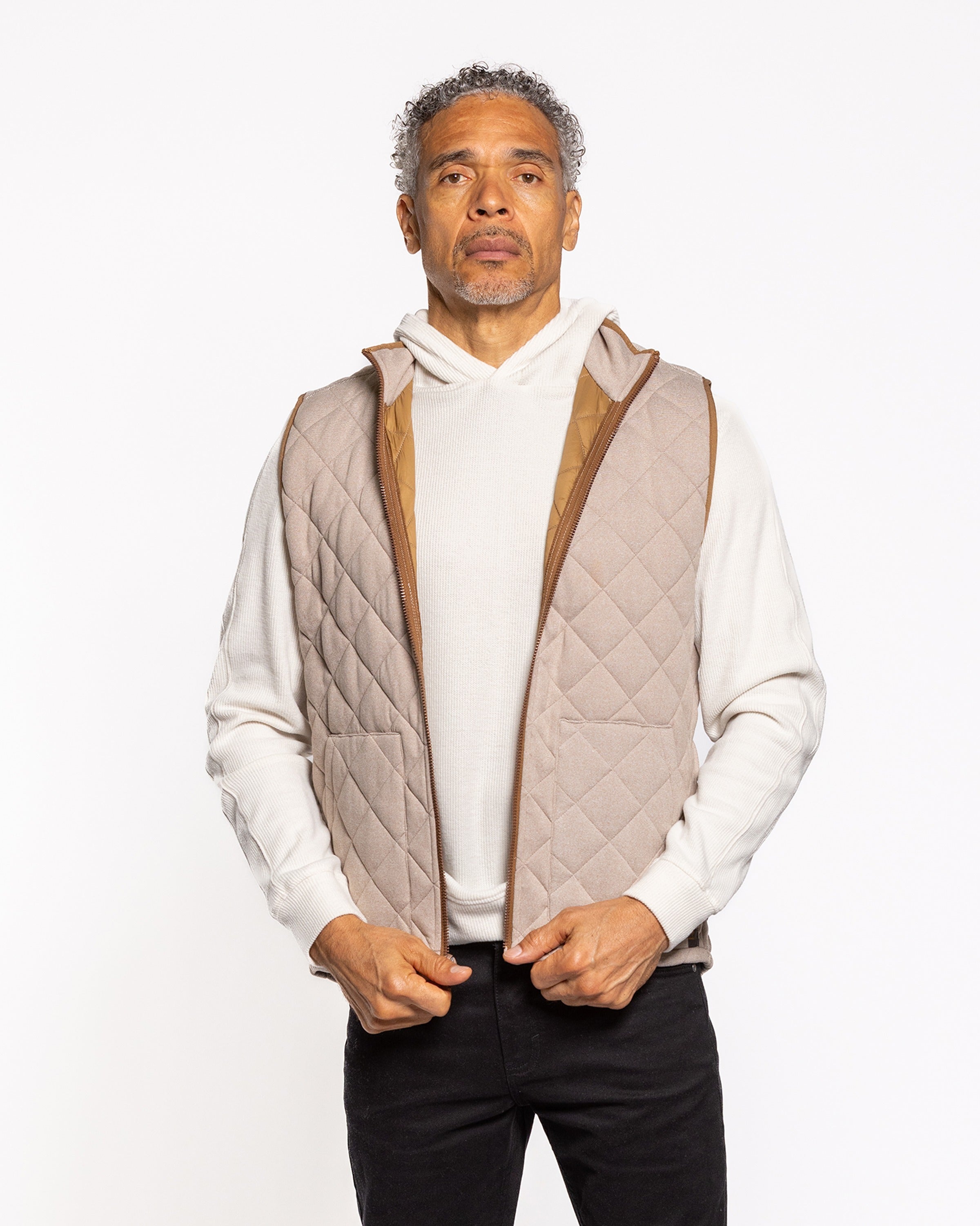 Quilted sleeveless tan vest with brown leather-trimmed armholes and front