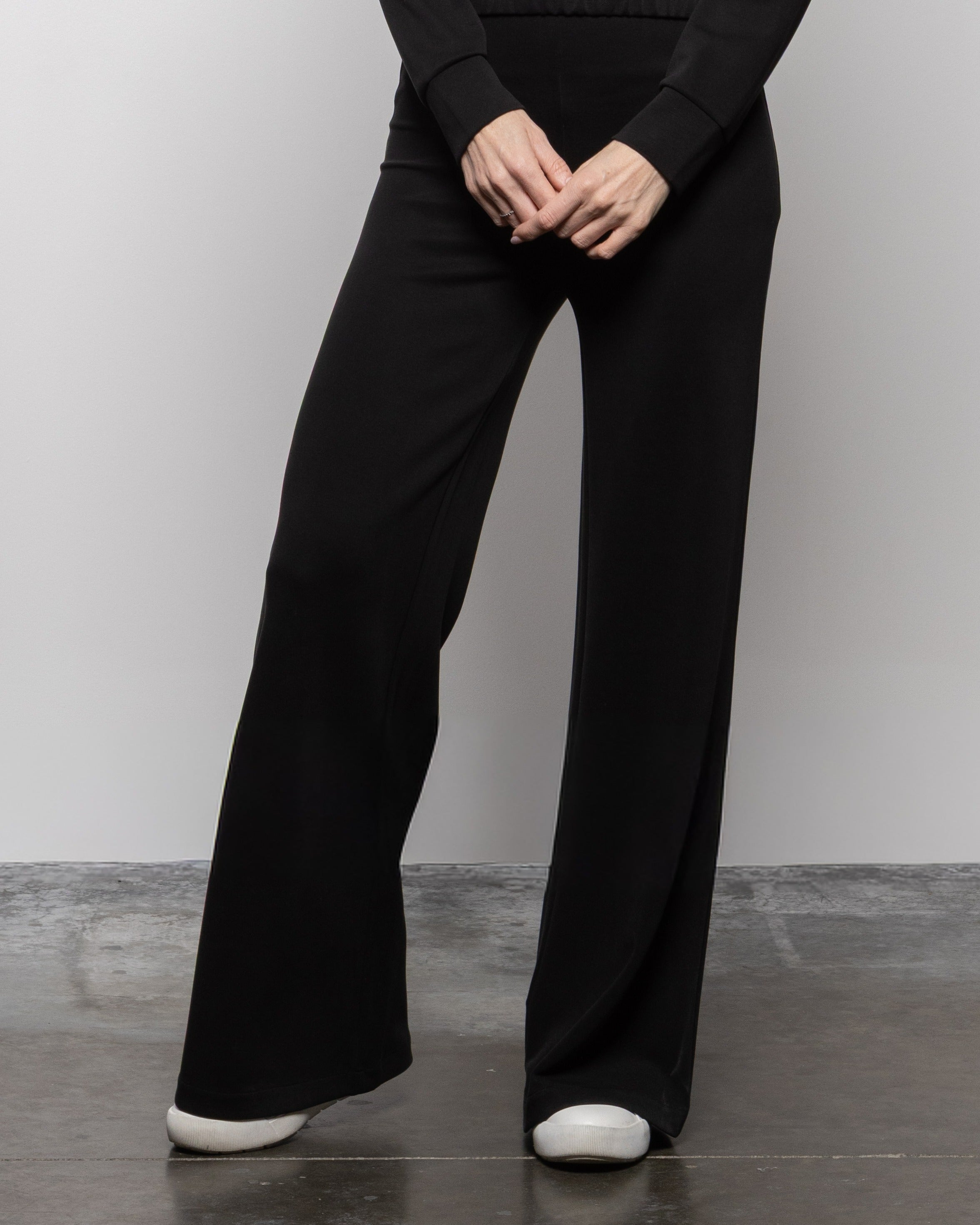 Matte black wide-leg pants, hands at waist, flared straight silhouette