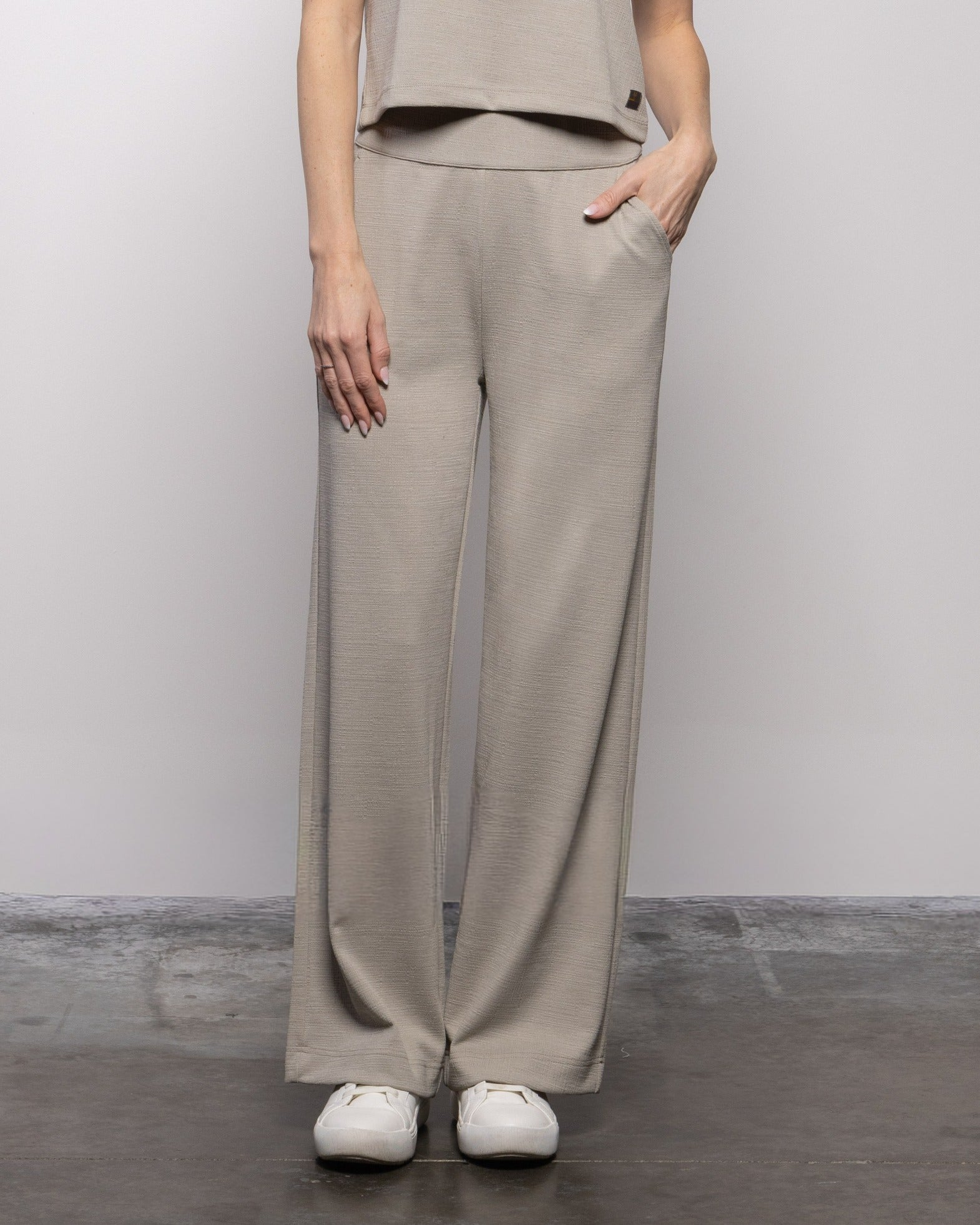 Beige textured wide-leg crop pants with elastic waist and side pockets, relaxed fit.