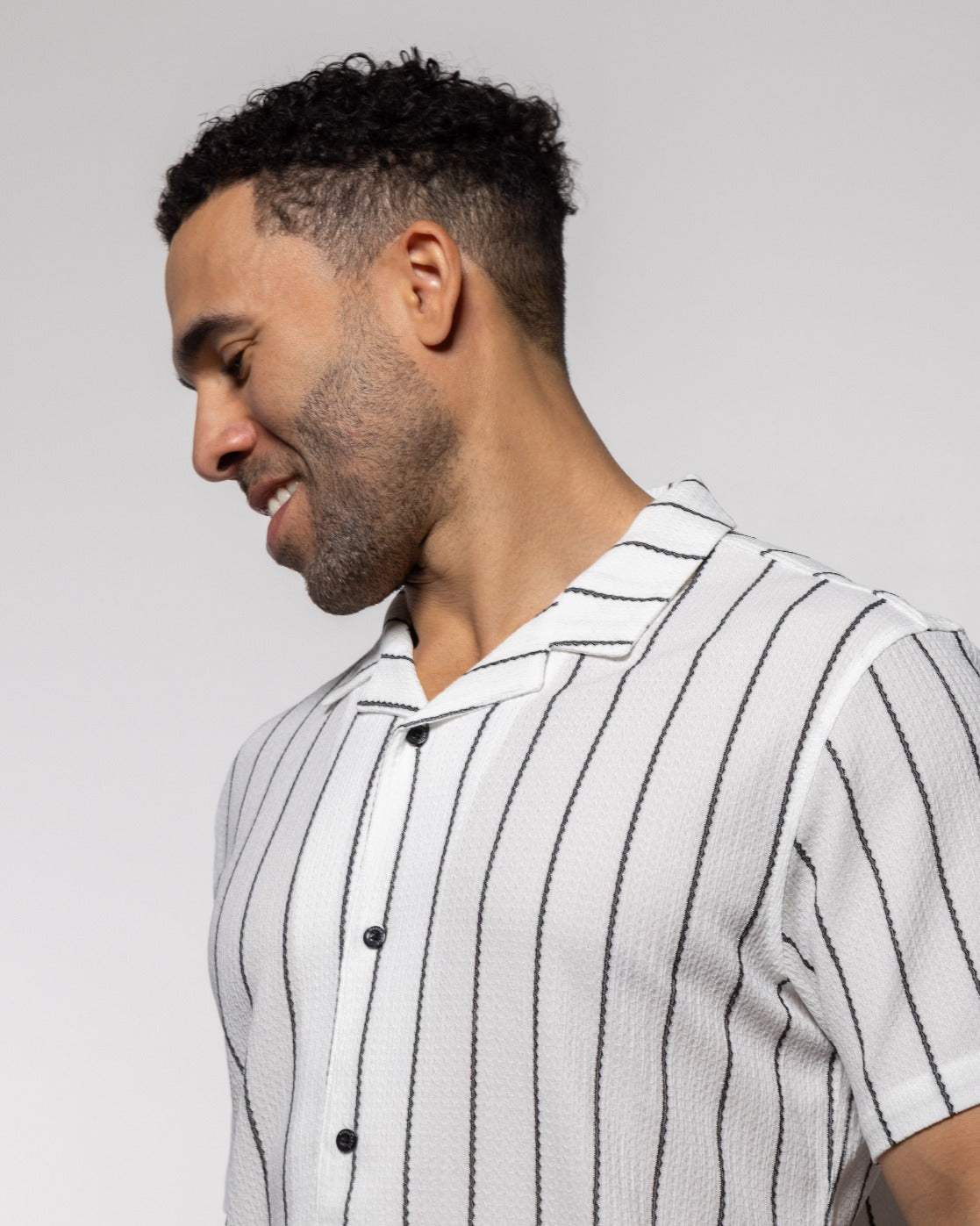Men's camp shirt in white with vertical black stripes, short sleeves, button front