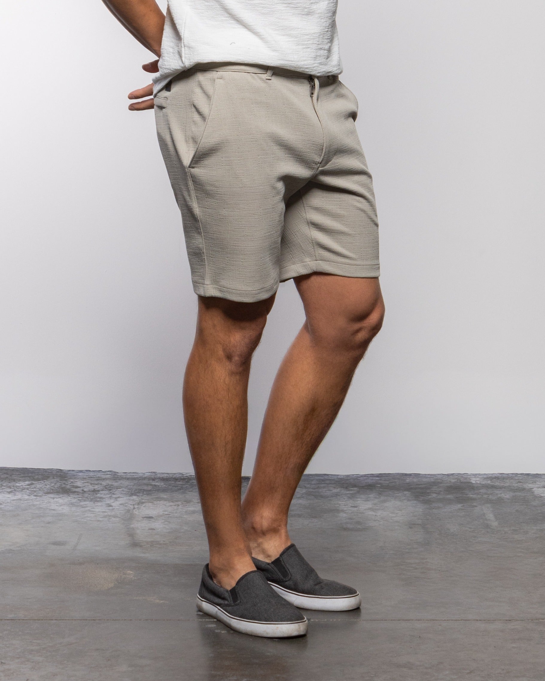 Light gray men’s chino shorts, side view, with belt loops and button fly