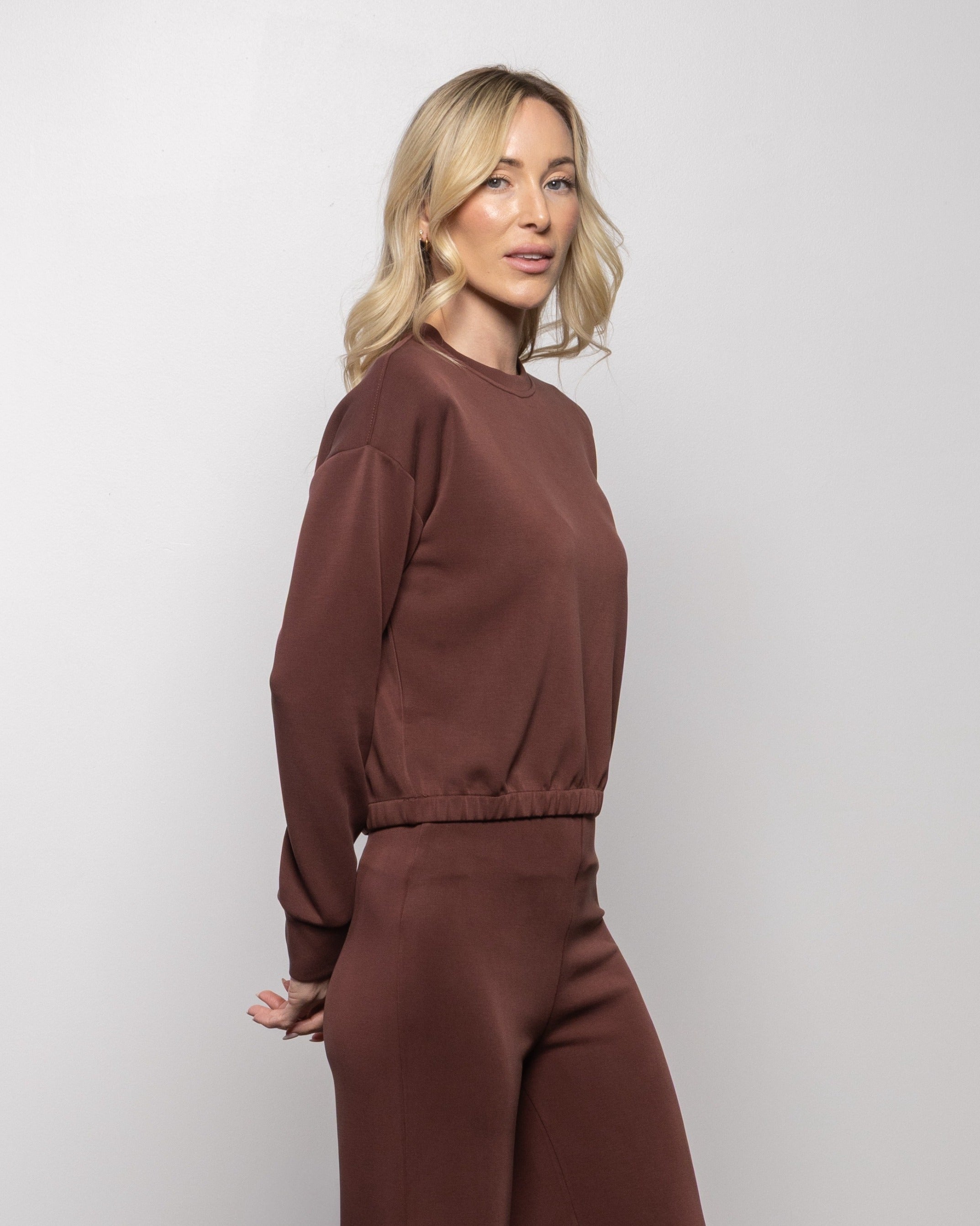 Brick brown crewneck sweatshirt, side view with long sleeves and elastic hem