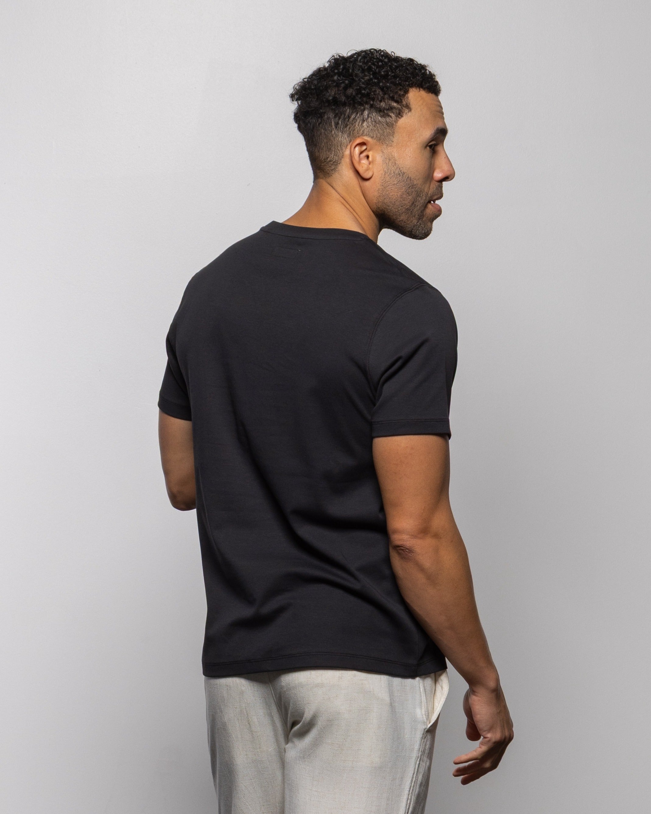 Jet black crew-neck short-sleeve T-shirt on model, side/back view