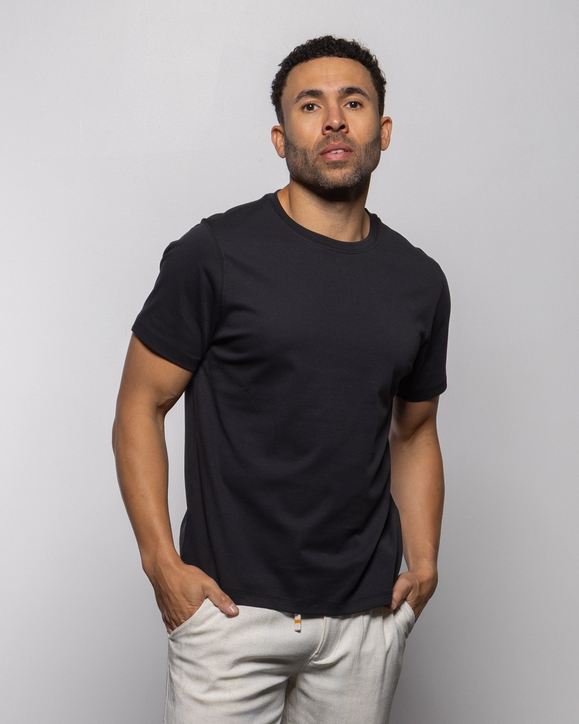 Jet black crew-neck short-sleeve T-shirt on model, front view with hands