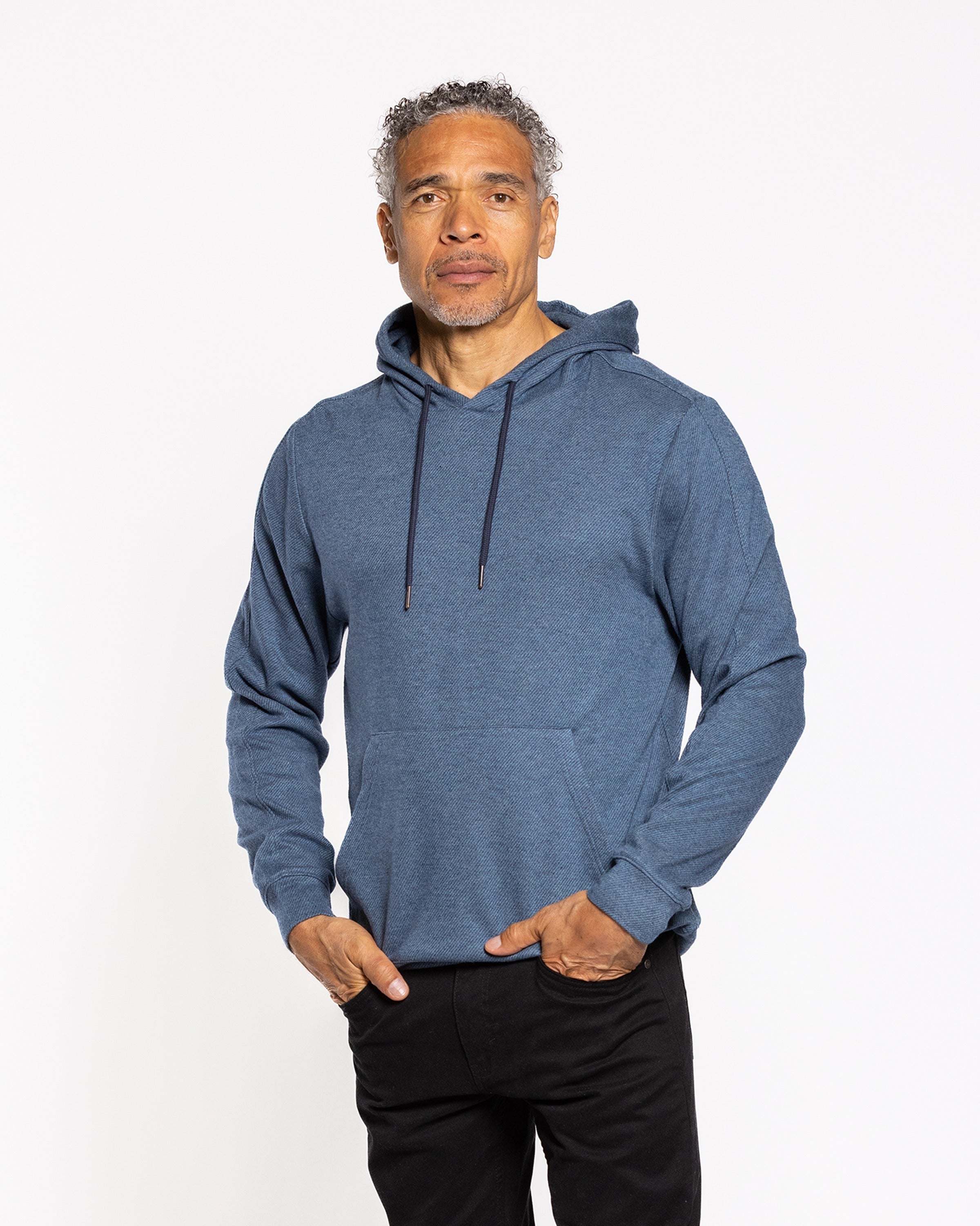 Indigo twill hood sweatshirt with drawstring hood and front pouch; hands in pocket